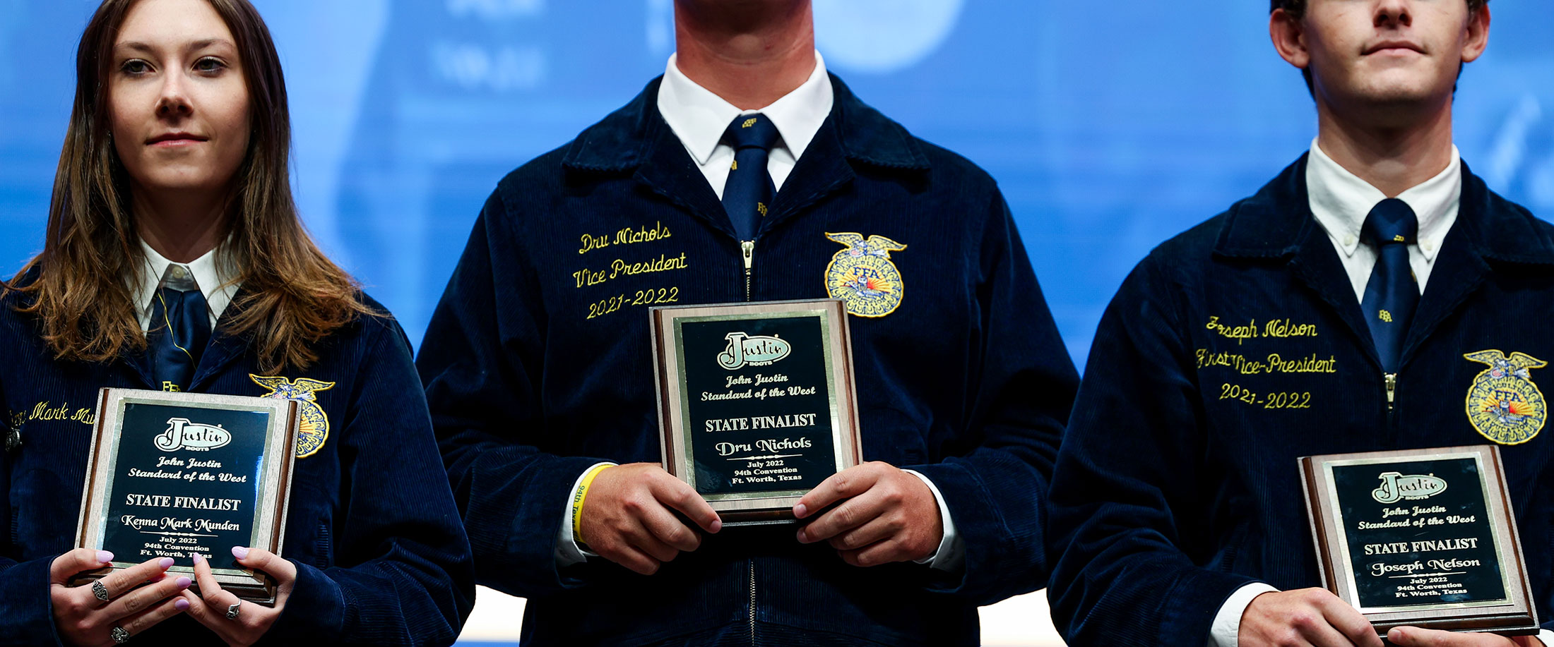 Three FFA members wearing blue corduroy jackets pose holding their plaques after receiving their FFA awards.